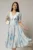 Rochie DY Fashion midi din triplu voal cu imprimeuri albastre bej si guler ascutit si nasturi la maneci
